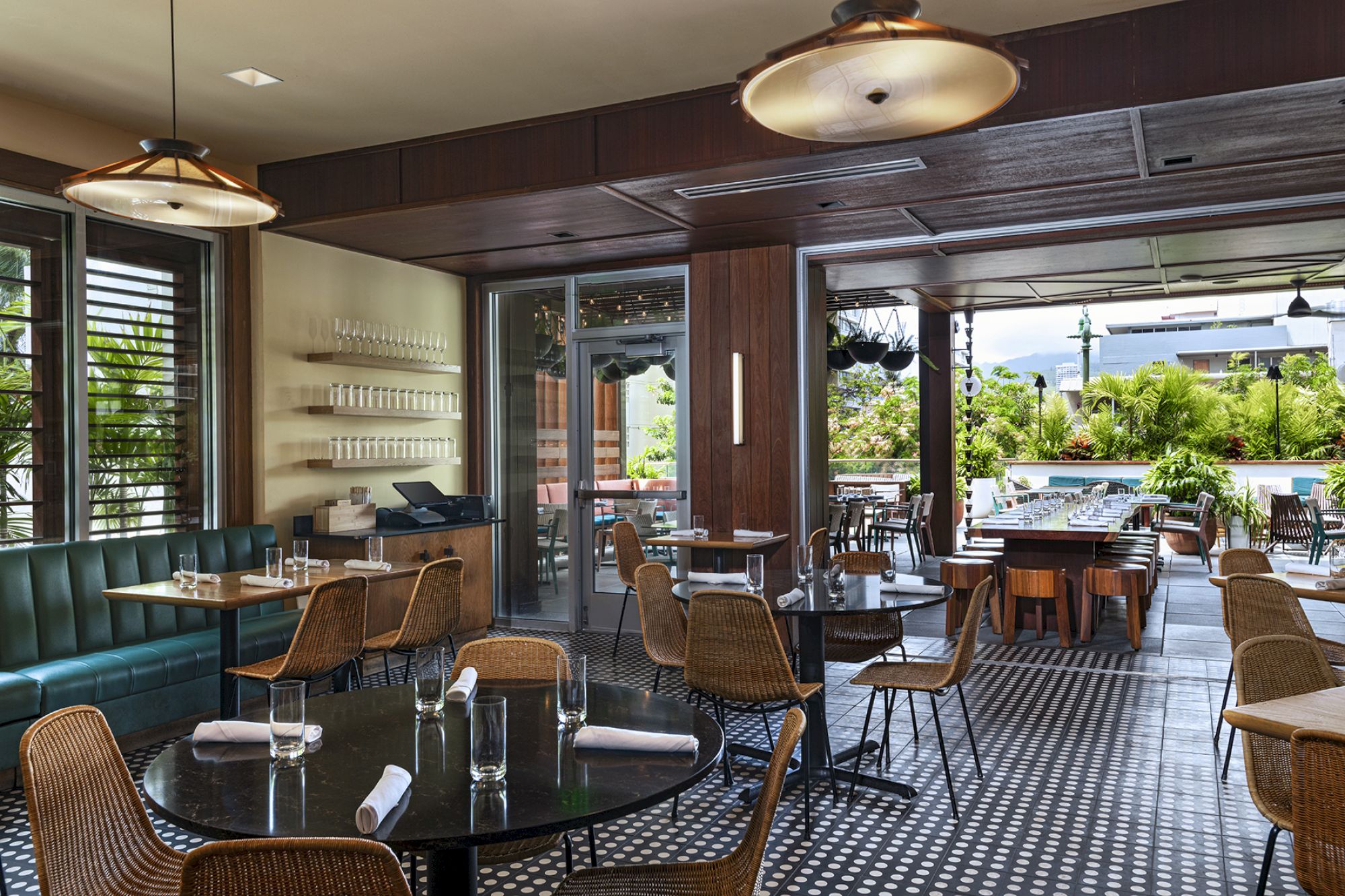 The image shows a stylish, modern restaurant interior with tables, chairs, and open doors leading to an outdoor seating area.